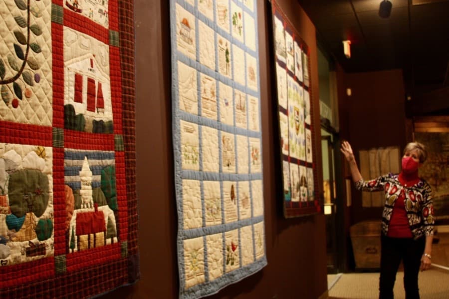 Tara Kohlenberg shows quilts that were created in celebration of the city's 150th anniversary. (Lauren Canterberry/Community Impact Newspaper)