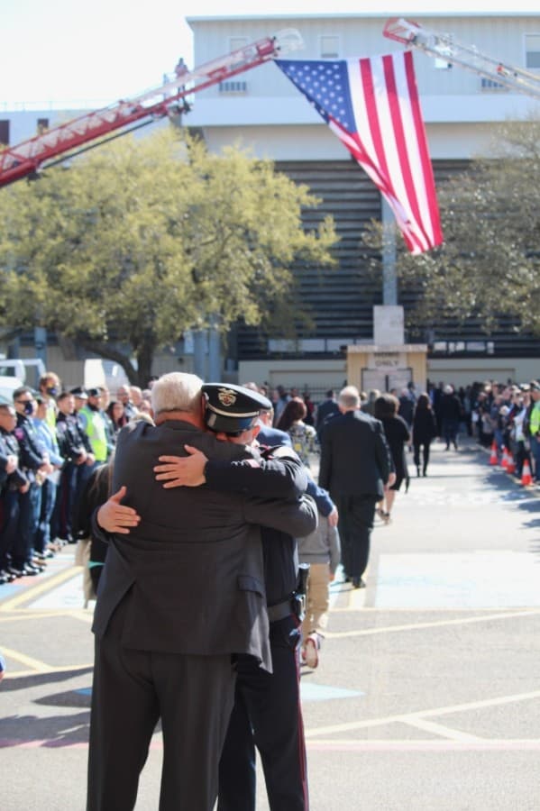 A first responder hugs a guest before City Manager Rob Hauck's memorial service March 19. (Anna Lotz/Community Impact Newspaper)