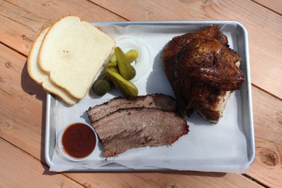 A tray of chicken and a 1/4 lb of brisket with pickles, onions and bread slices, served with barbecue sauce. (Photos by Megan Cardona/Community Impact Newspaper)