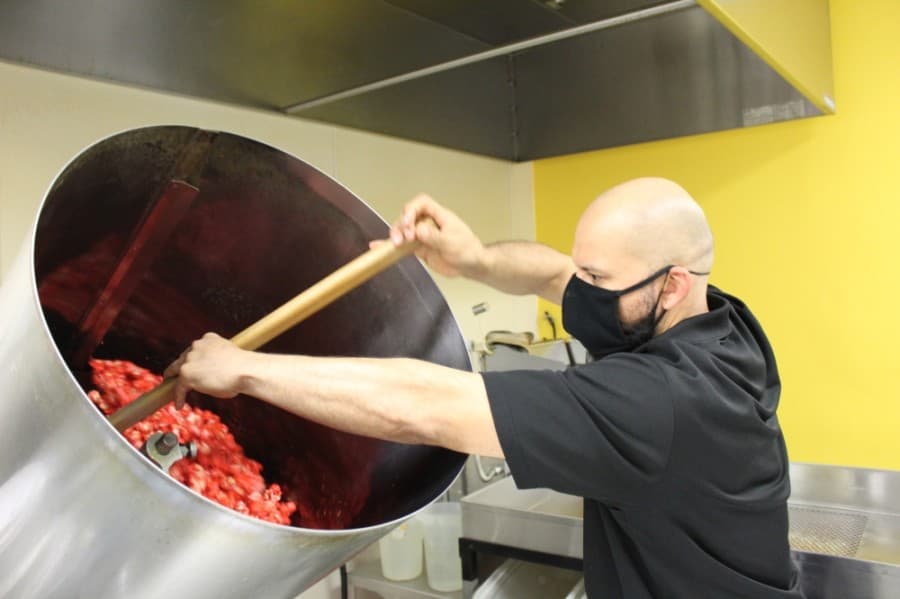 Mario Navarrete, one of the owners of Popcorn Blast, mixes a batch of popcorn for a customer order in one of two large mixing machines on-site. (Shawn Arrajj/Community Impact Newspaper)