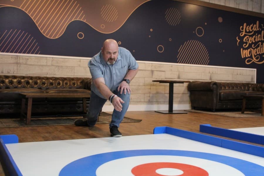 Michael Goss, Austin’s Park n’ Pizza president and co-owner, throws a rock on the street curling sheet. (Megan Cardona/Community Impact Newspaper)