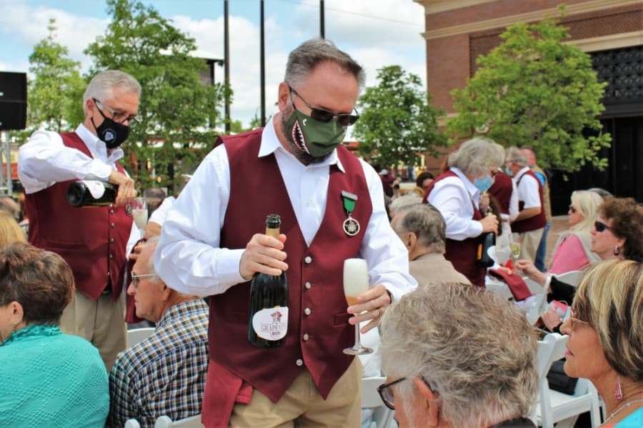 Members of the Grapevine Wine Pouring Society fill up guests' glasses ahead of the toast during the Grapevine Main Station grand opening celebration on April 24, 2021. (Sandra Sadek/Community Impact Newspaper)