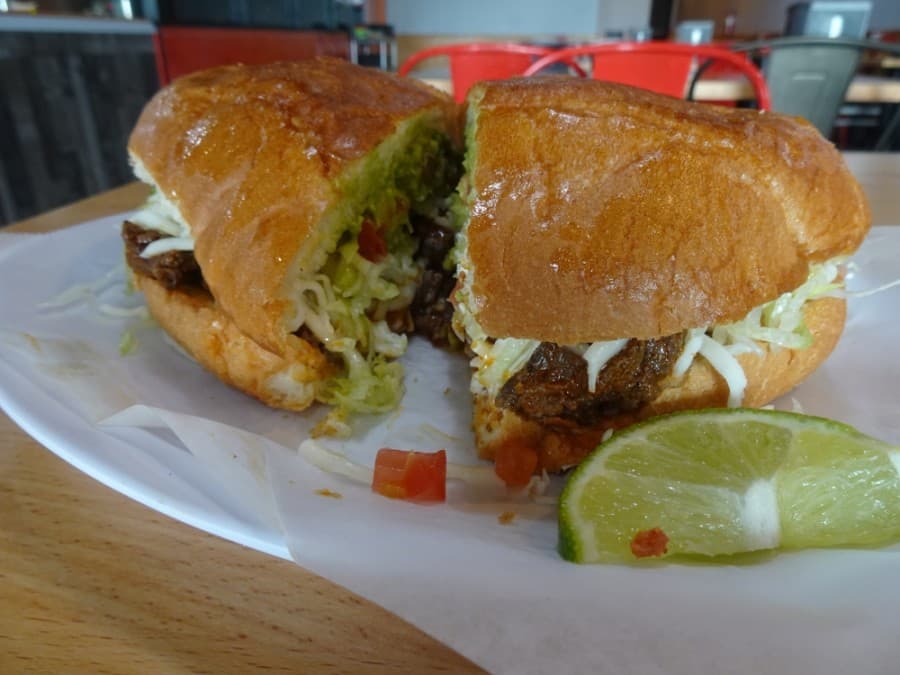 The torta contains beans, lettuce, tomato, cheese, crema, guacamole and a choice of meat. (Danica Lloyd/Community Impact Newspaper)
