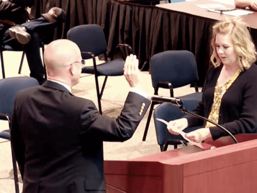 Tom Heslep with his hand up while he is sworn in.