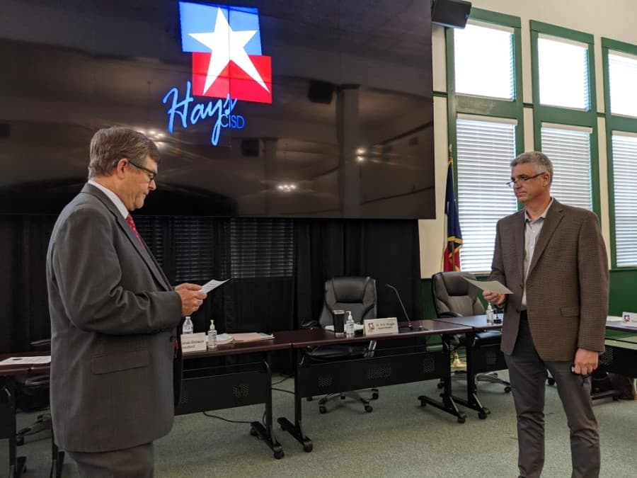 Hays CISD trustee Will McManus (right) was sworn in for his second term by Hays County Precinct 2 Commissioner Mark Jones (left) during a May 17 meeting. (Warren Brown/Community Impact Newspaper)