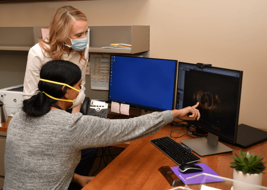 doctors point to computer screen to discuss patient case