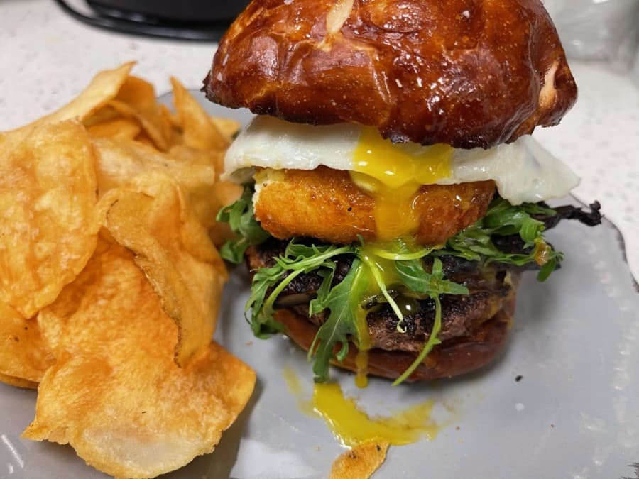Vegetarian OMG Goat Cheese Burger ($18)
Grilled portobello mushroom, sherry onions, arugula, espresso aioli, fried goat cheese, over easy egg on a pretzel bun (Courtesy Harvest Kitchen & Bakery)