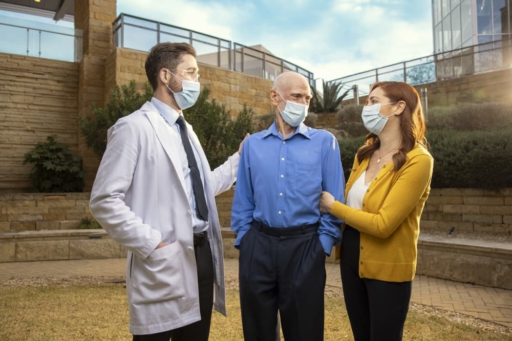doctor greeating a patient and his caregiver outside hospital