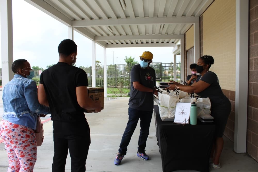 Food incentives are one of several ways health care systems and local governments are trying to get more people vaccinated. Staff with the nonprofit Lucille’s 1913 hand out prepared meals to people who attended a vaccine drive targeting the Independence Heights community in May. (Shawn Arrajj/Community Impact Newspaper)