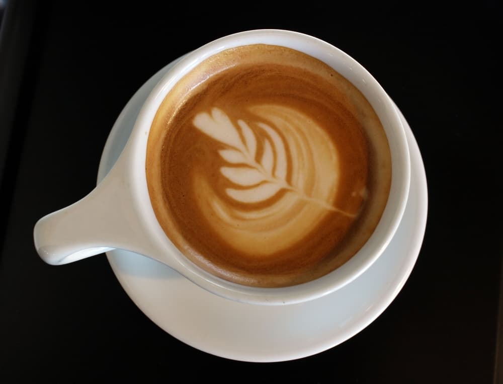 an aerial view of a 12-ounce latte with a cream design