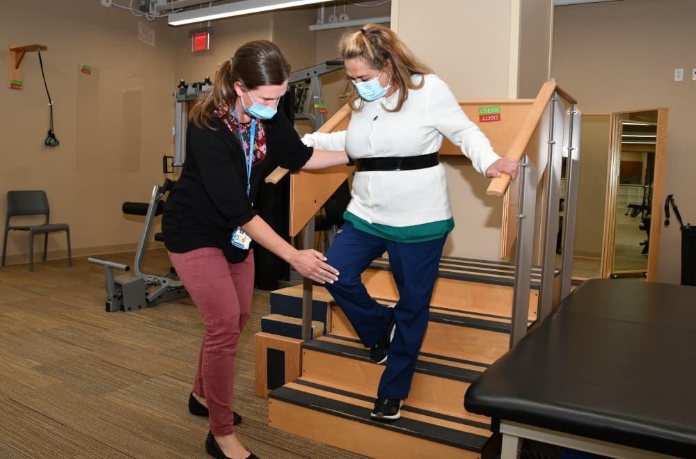 therapist helping patient down stairs