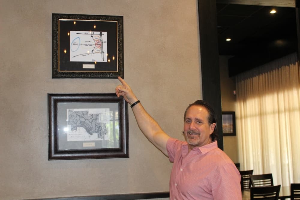 The Republic Grille owner Terry McBurney points out a replica of the napkin on which The Woodlands founder George Mitchell drew his vision for the community. (Ally Bolender/Community Impact Newspaper)