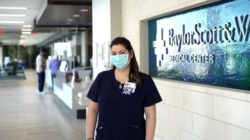 nurse standing in front of Baylor Scott & White Health sign