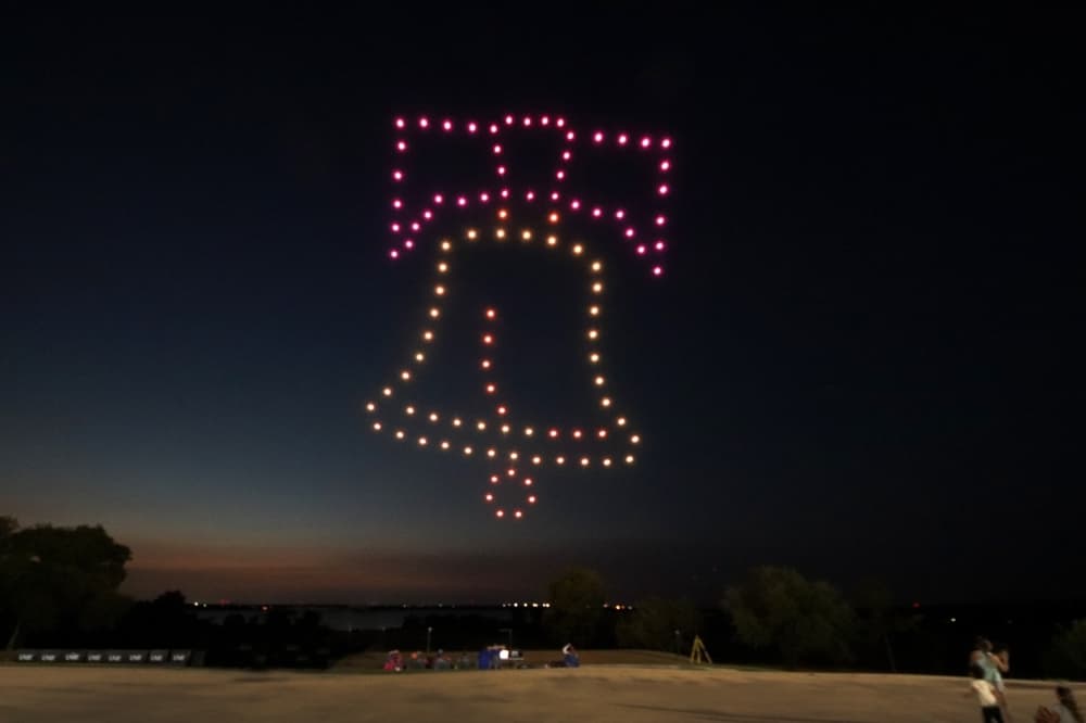 Drones at night lighting up in the shape of the Liberty Bell