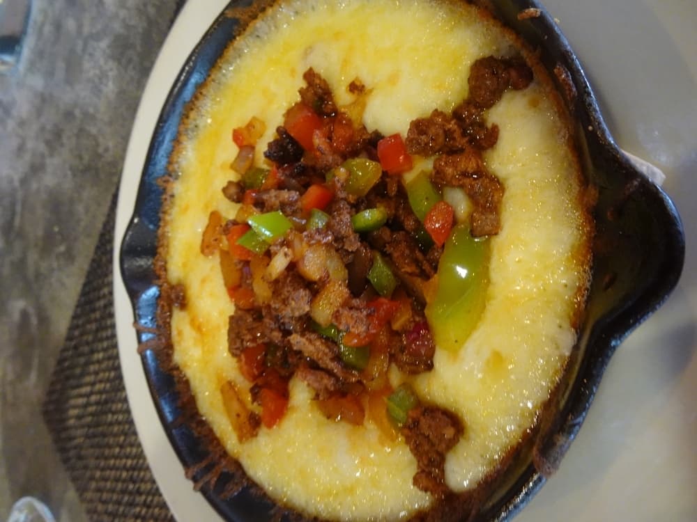 The queso flameado appetizer features melted white cheese with mushrooms, peppers and onions topped with choritzo and pickled peppers on a hot skillet ($9.99). (Emily Jaroszewski/Community Impact Newspaper)