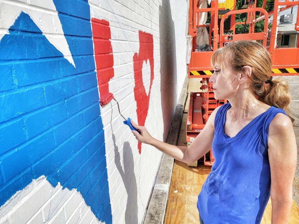 Beth Mankin Jones is painting the city's mural at the visitor and information center on West Main Street. (Courtesy Mike Baxter)