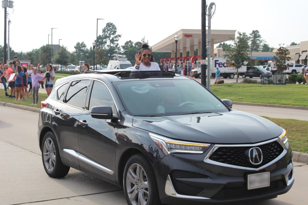 Jordan Chiles smiles and waves from the sunroof of a vehicle. (Ally Bolender/Community Impact Newspaper)