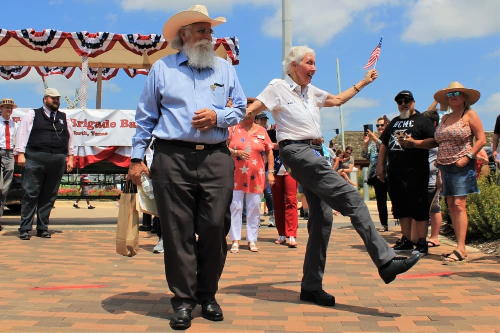 Wally Funk, accompanied by Paul McCallum, executive director of Grapevine's Convention and Visitors' Bureau, dances as she makes her way to the stage. (Sandra Sadek/Community Impact Newspaper)