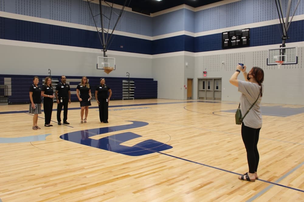 Frisco ISD board members stop to take a photo at the main gym in Emerson High School during the Aug. 9 tour. (Miranda Jaimes/Community Impact Newspaper)