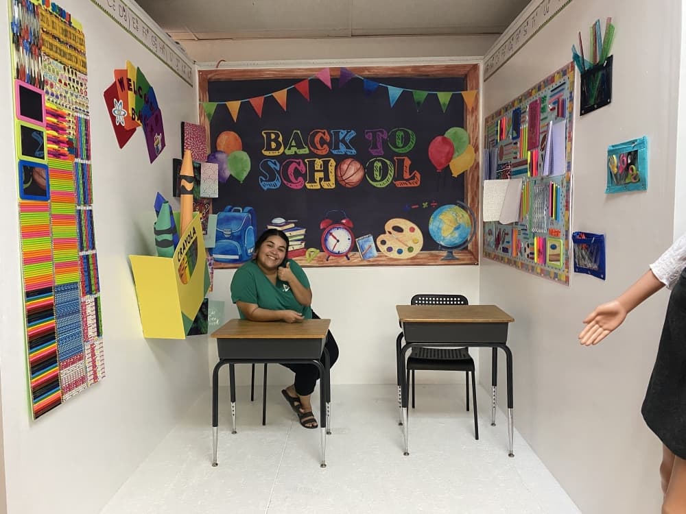 Picture Perfect team lead Sasha Lerma poses in the back-to-school-themed room of the selfie gallery, which has different themed rooms for photo taking. (Brooke Sjoberg/Community Impact Newspaper)