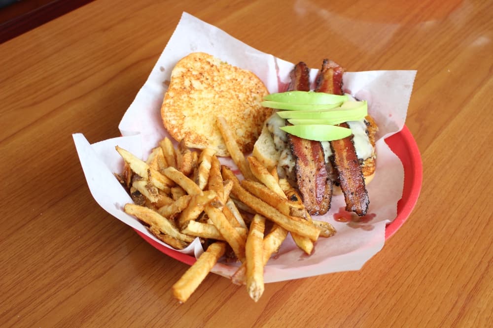 The Ultimate Rattlesnake Burger ($17) comes with smoke-peppered bacon, avocado on a jalapeño cheddar sourdough bun with a side of fries. (Andrew Christman/Community Impact Newspaper)