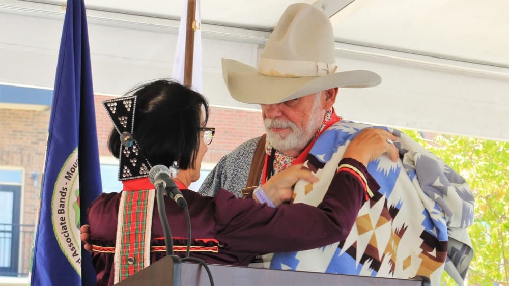 woman giving blanket to mayor