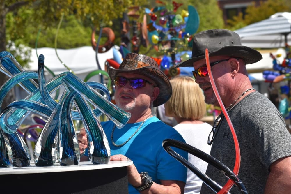 two men observe a glassware sculpture at Art in the Square