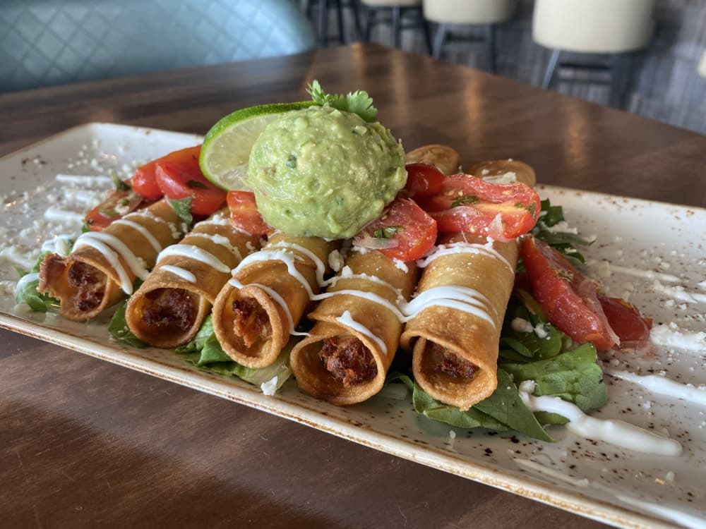 The flauta plate features five roasted chicken flautas in corn tortillas with toppings. (Ally Bolender/Community Impact Newspaper)