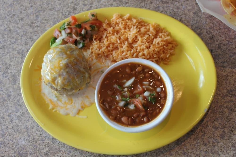 The stuffed avocado ($13) is served with sides and tortillas and can be stuffed with ground beef or shredded chicken for an additional $3. It is battered and lightly fried, then topped with a cream sauce and cheese. (Colleen Ferguson/Community Impact Newspaper)