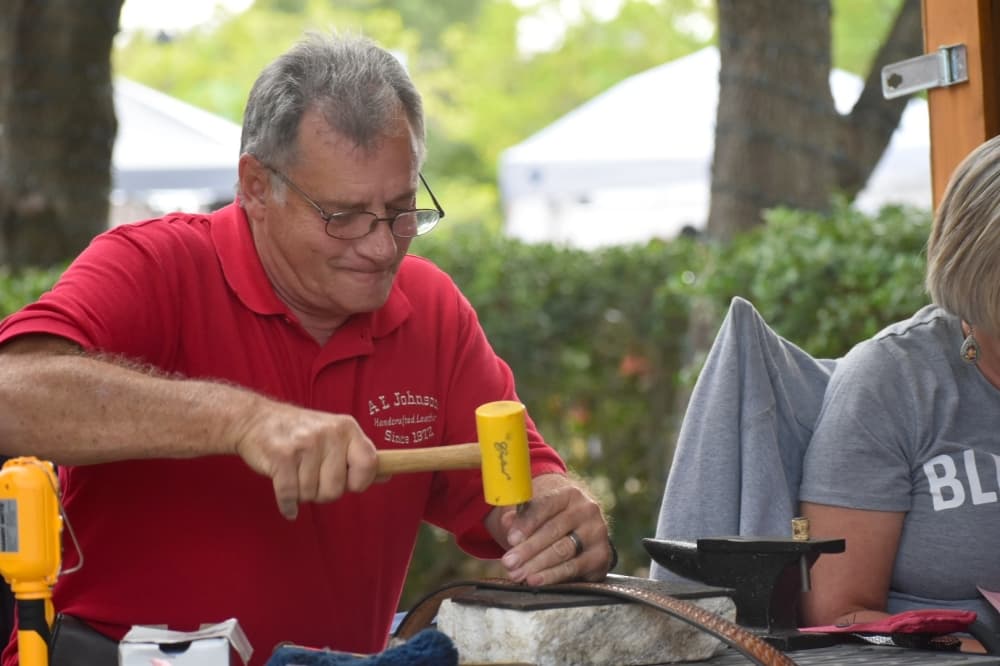 Arden Johnson hammers a belt at Oktoberfest on Oct. 17 in Southlake Town Square. (Anjali Krishna/Community Impact Newspaper)