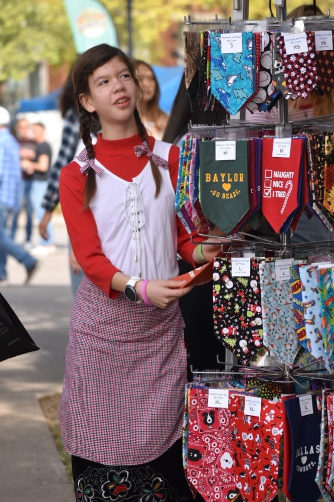 Kaedyn Madins looks at kerchiefs at Oktoberfest on Oct. 17 in Southlake Town Square. (Anjali Krishna/Community Impact Newspaper)