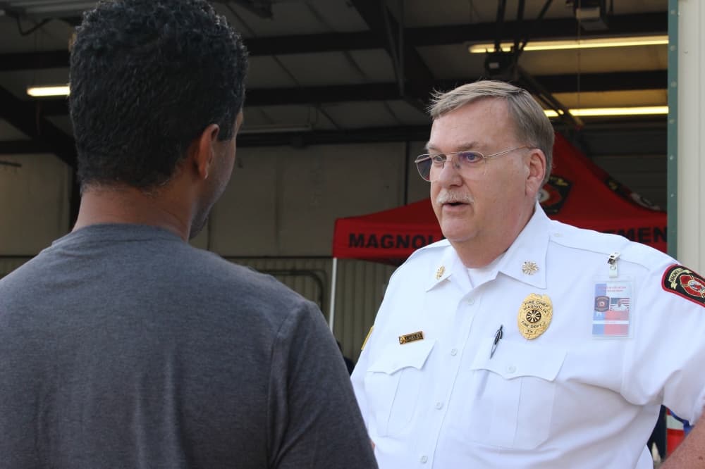 Jeff Hevey, the chief of the Magnolia Volunteer Fire Department, speaks with a community member during the Oct. 19 community event. (Chandler France/Community Impact Newspaper)