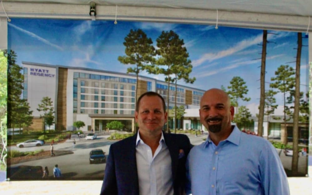 Czajkoski and Williams in front of a rendering of the hotel exterior