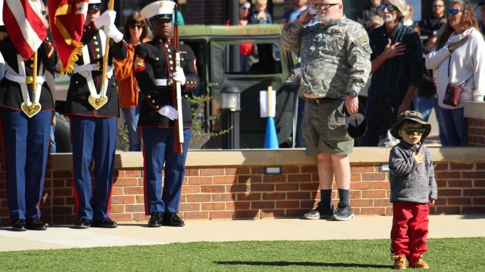 A boy stands for the pledge of allegiance and the national anthem in front of Roanoke City Hall on Nov. 6. (Sandra Sadek/Community Impact Newspaper)