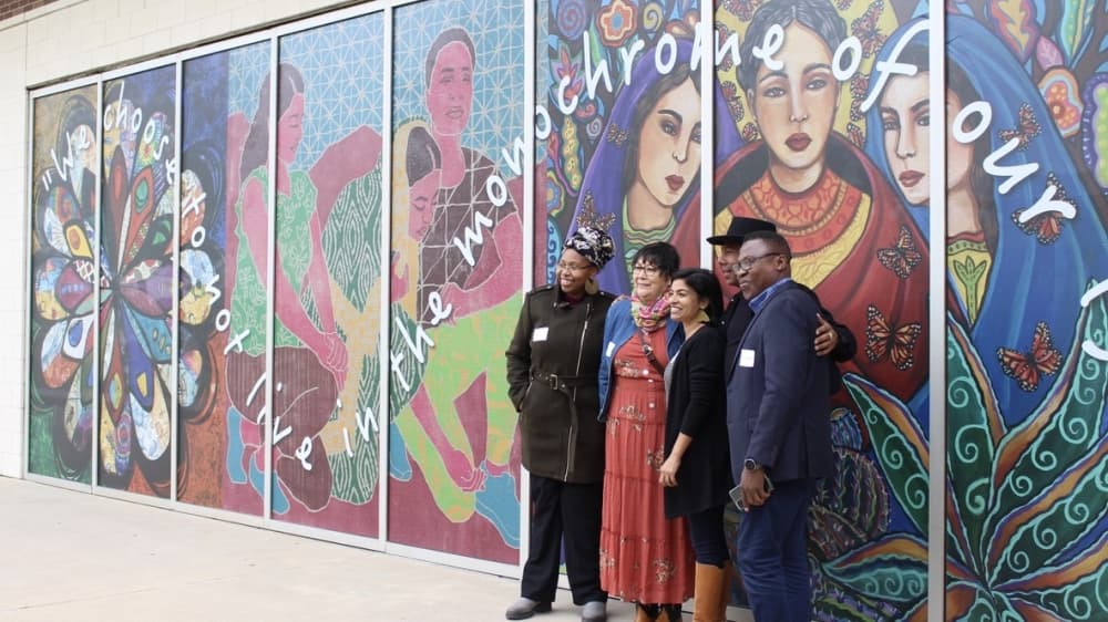 Artists involved in the project pose in front of the newly installed "Diversity over Division" mural. (Claire Shoop/Community Impact Newspaper)