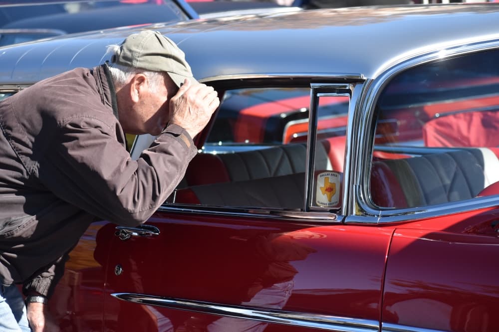 Doug Cook inspects the interior of a classic Chevrolet. (Anjali Krishna/Community Impact Newspaper)