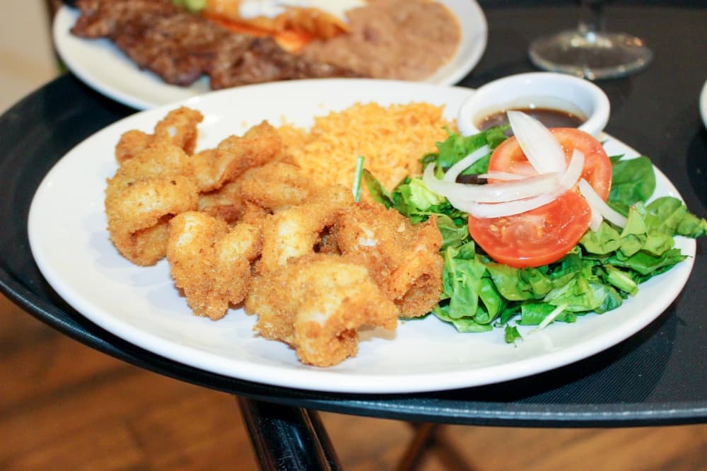 The Shrimp Sizzler ($15.50): A plate of fried shrimp is served with garlic mojo with ginger and sautéed vegetables. (Wesley Gardner/Community Impact Newspaper)