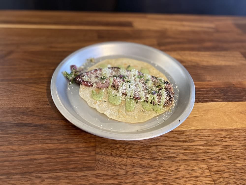 The sliced brisket taco ($7) is topped with avocado salsa, Texas gremolata and cotija cheese. (Trent Thompson/Community Impact Newspaper)