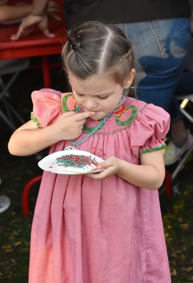 Charlotte Benedick enjoys a Christmas cookie at Roanoke's Hometown Holiday event. (Anjali Krishna/Community Impact)