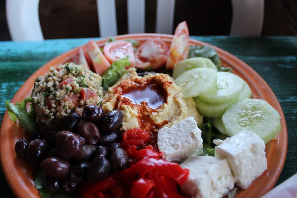 The Fellowship Platter ($13.99): Roasted garlic hummus is served with tabouli, kalamata olives, feta, roasted red peppers, tomatoes and cucumbers with a side of pita bread. (Sierra Rozen/Community Impact Newspaper)