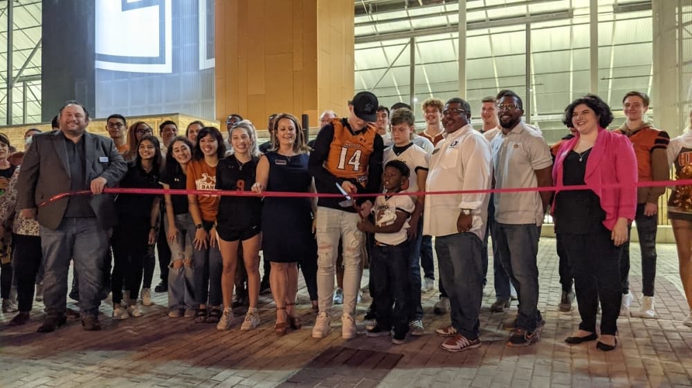 Two student athletes cut the ribbon outside the stadium.