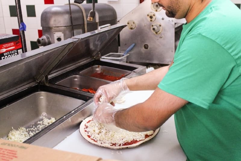 Iqbal prepares a thin crust Fabulous Four pizza to order, one of the top sellers along with the Monster Pizza.