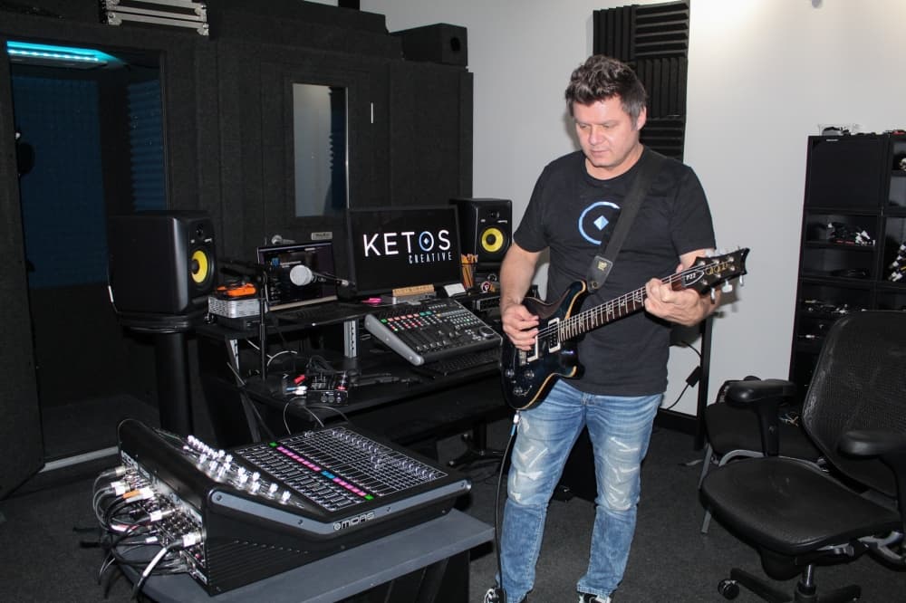 While playing his favorite guitar, Allen Joanis said his production studio is his “home away from home.” (Bailey Lewis/Community Impact Newspaper)
