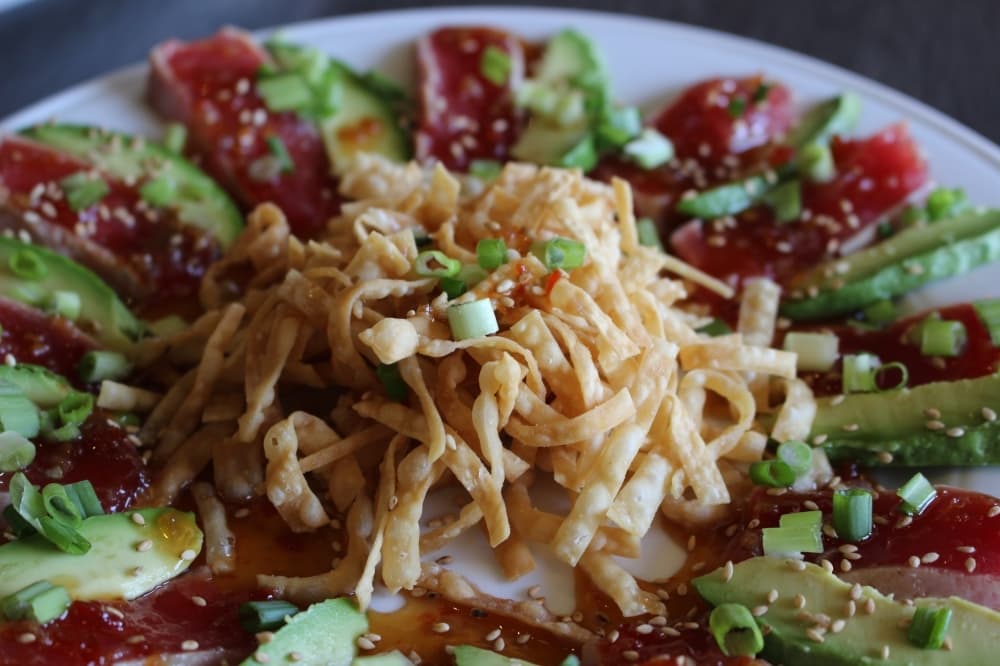 The seared tuna appetizer ($12.95) is served with a side of avocado next to the tuna. (Sierra Rozen/Community Impact Newspaper)