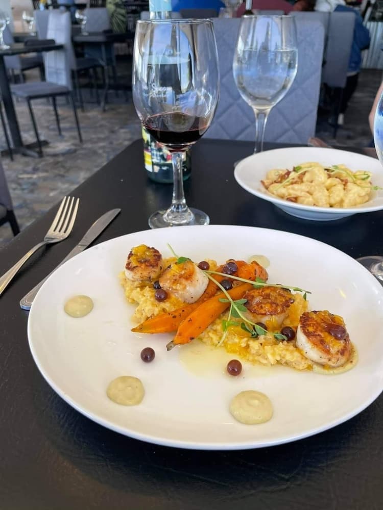 Seared Scallop Risotto: Seared Sea Scallops are served over a Parmesan Risotto with a Mandarin orange butter and passion fruit pearls.
