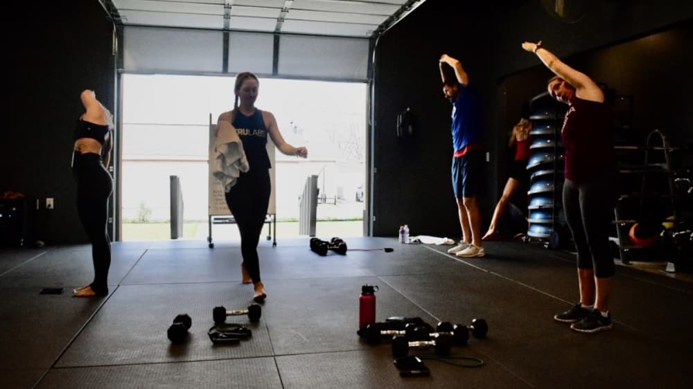 Members at Karma Fitness Studio practice strength yoga inside a room with an open garage. (Matt Payne/Community Impact Newspaper)