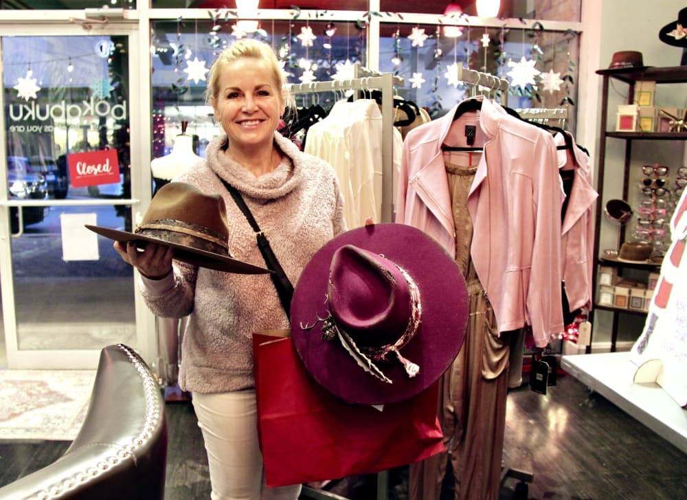 Hat artist Angel Coe holds two of her creations that are sold at Bokabuku. (Sumaiya Malik/Community Impact Newspaper)