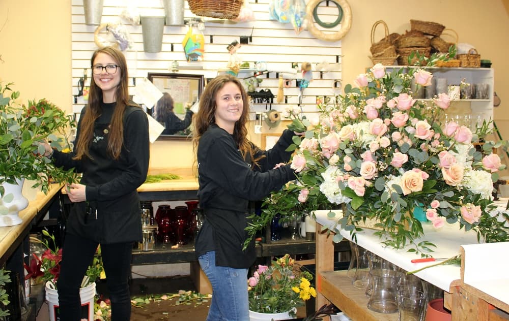 Rebecca Williams, left, and Rebecca Binket assist with an arrangement featuring dusty rose roses. (Karen Chaney/Community Impact Newspaper)
