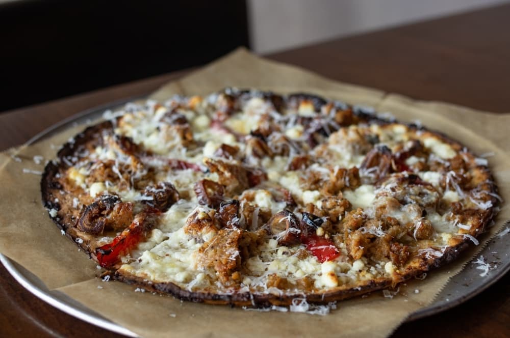 
Pizza #13 is made with Italian sausage, dates, red bell pepper, goat cheese, asiago, roasted garlic puree and crushed red pepper.