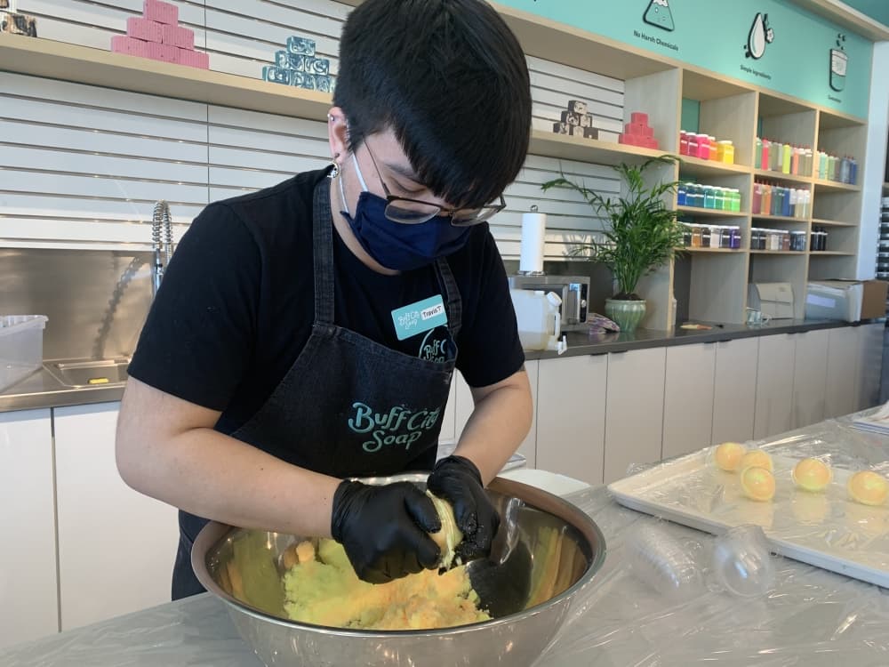 An employee makes bath bombs at the grand opening of Buff City Soap. (Zara Flores/Community Impact Newspaper)